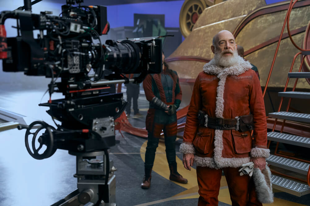 Behind the scenes shot of J.K. Simmons as Santa Claus standing next the camera